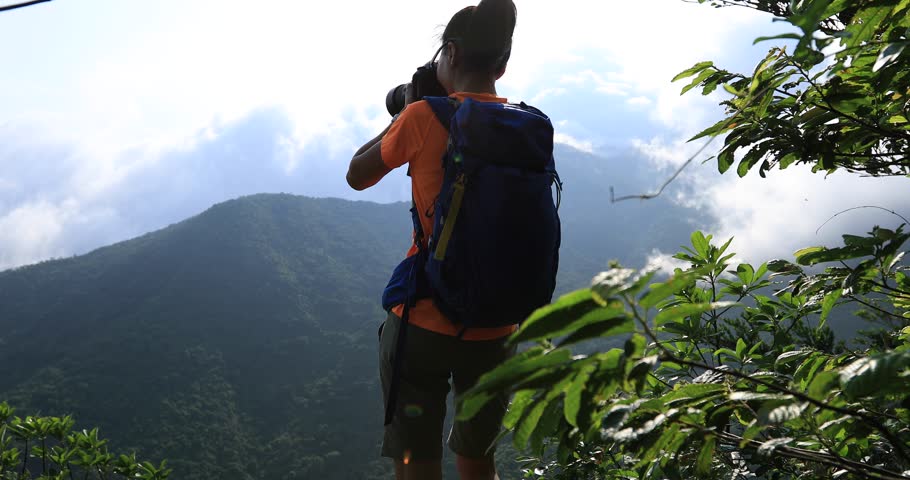 Woman photographer taking pictures in sunrise mountain