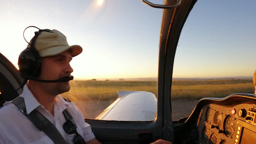 General Aviation Pilot in Cockpit with Flight Instruments Panel and Sunny Sky View. Young Male Pilot in Aviation Headset Controls Light Plane Cockpit During Daytime Flight