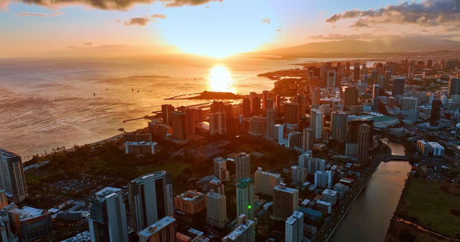 Soft orange light of sunset covering the cityscape of Honolulu, Hawaii, USA. Aerial perspective on Waikiki resort and waterscape of the Pacific.