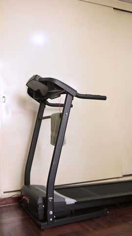 Fit woman in sportswear getting on a treadmill, attaching the safety clip, and starting her cardio workout routine indoors, focusing on a healthy and active lifestyle for fitness and wellbeing