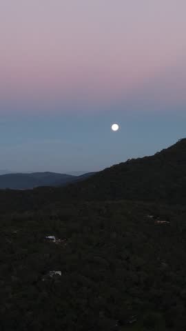 Cityscape at dusk under a bright full moon. Scenic night view from a viewpoint with moonlight reflecting over the urban environment.