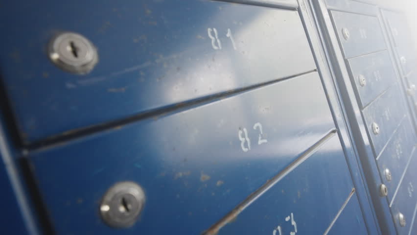 Rows of Blue Metal Mailboxes with Numbers and Locks in Apartment Building | Dutch Angle Ultra-Wide Close-Up View | Urban Residential Postal Infrastructure