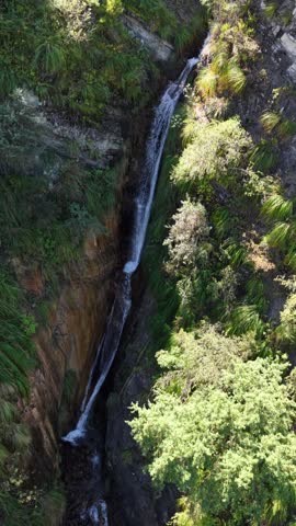 Double-drop waterfall cascading from a cliff in the heart of a rocky ravine.