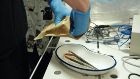 Male hands in blue sterile gloves handling sterilized surgical instruments. Unpack medical instruments onto tray surface. Medical professionals arrange tools in clinical setting. Preparing for surgery - Powered by Shutterstock - Get 15% off with code: PIKWIZARD15