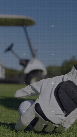 Vertical video: Gloved hand placing golf ball on blue tee starting tech HUD over ball readying shot. Overlay, grid, perspective, outdoor, course, greens, vertical video