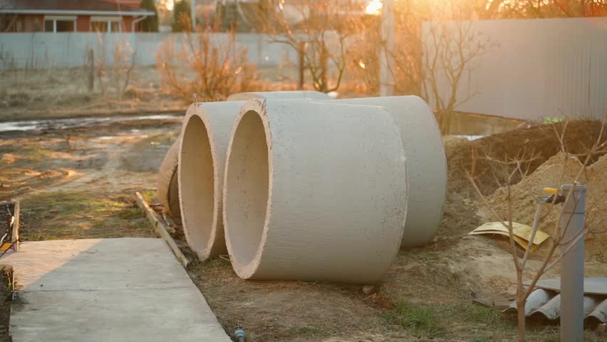 Two large concrete rings at construction site in rural backyard at sunset