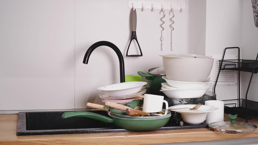 Pile of dirty dishes with food leftovers in the kitchen sink ready for washing after a party