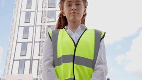 A young woman wearing a safety vest gives instructions on a construction site. She uses a megaphone while standing under a clear sky with tall buildings. - Powered by Shutterstock - Get 15% off with code: PIKWIZARD15