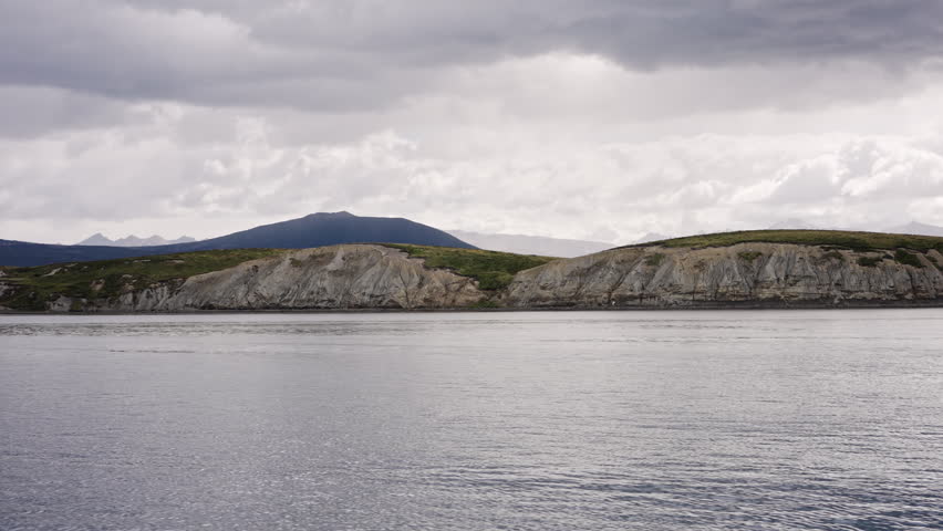 Rocky Coastline Across Calm Water In Overcast Light