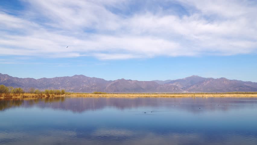 Serene Vertical Landscape of Calm Lake with Mountain Range Reflection Under Clear Blue Sky with Wispy Clouds Nature Photography