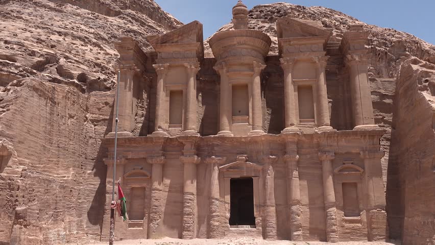 An ancient city in Jordan. Stone structures and cliffs surround them. The site shows history and architecture from long ago.