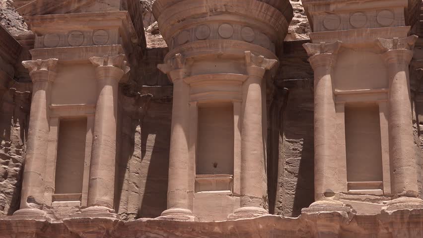 An ancient city in Jordan. Stone structures and cliffs surround them. The site shows history and architecture from long ago.