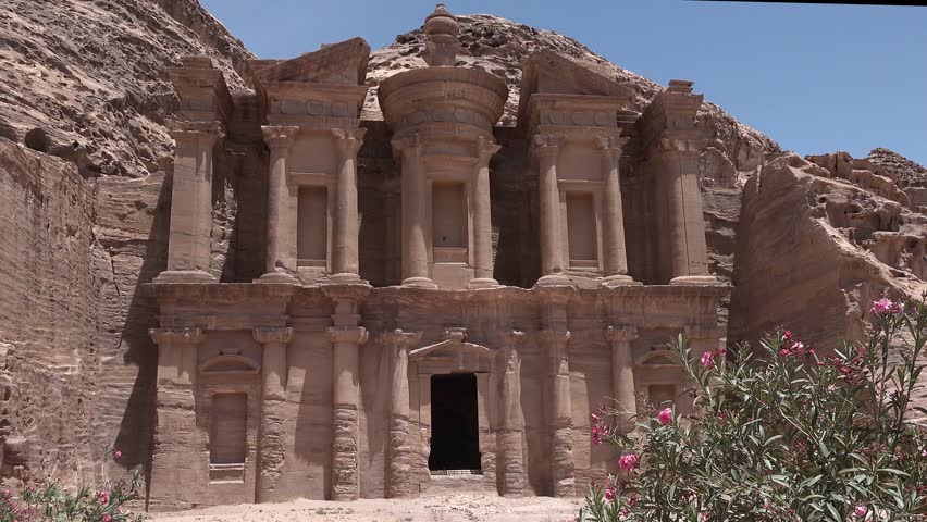 An ancient city in Jordan. Stone structures and cliffs surround them. The site shows history and architecture from long ago.