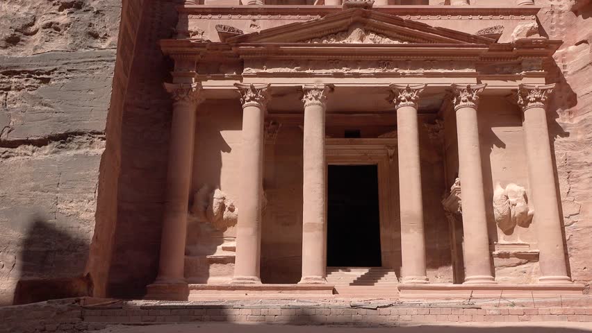 An ancient city in Jordan. Stone structures and cliffs surround them. The site shows history and architecture from long ago.