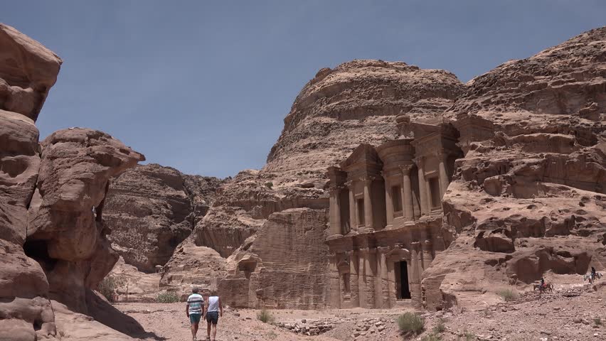 An ancient city in Jordan. Stone structures and cliffs surround them. The site shows history and architecture from long ago.