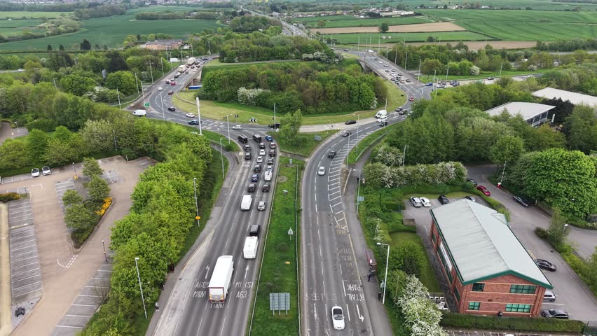 Aerial view of city traffic at a major road intersection, Aerial view of a green landscape with a busy highway intersection.