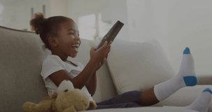 Girl tapping touchscreen, shifting on sofa, initiating green world-map animation for education. Child, device, tablet, home, teddy, plush, cozy - Powered by Shutterstock - Get 15% off with code: PIKWIZARD15