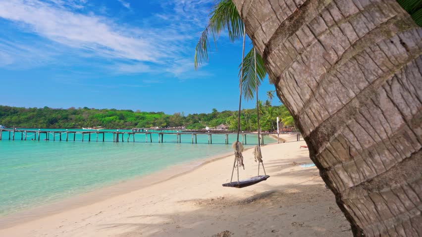 Thailand tropical island with a paradise white sand beach and coconut trees. Blue ocean off the sandy coast on a sunny summer day. Summer vacation and tropical beach concept.