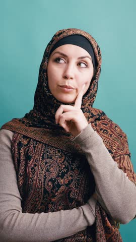Pretty muslim woman in traditional hijab thinking and having an eureka moment. She raises her finger after finding a solution to a problem. Vertical
