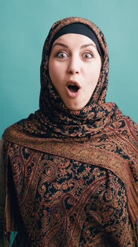 Young arab woman in a traditional headscarf expressing a wide range of emotions, from surprise and joy to anger and celebration. Vertical