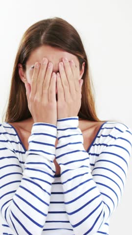 Woman hiding her face with her hands against white background