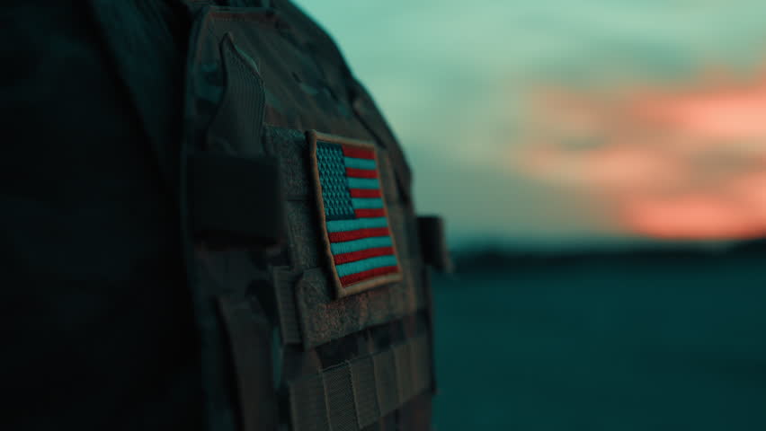American Flag on the Chest of an American Soldier Uniform on the Beach at Sunset