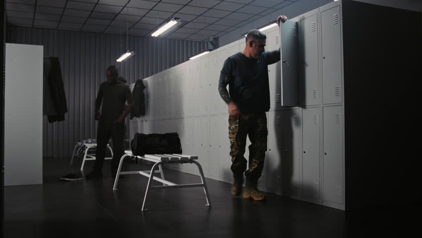Three Athletic Soldiers in Uniforms in Locker Room, Chat Casually, Dressing and Preparing Gear For Mission or Combat Training on Base. Concept of Team Interaction, Military Service and Preparation.