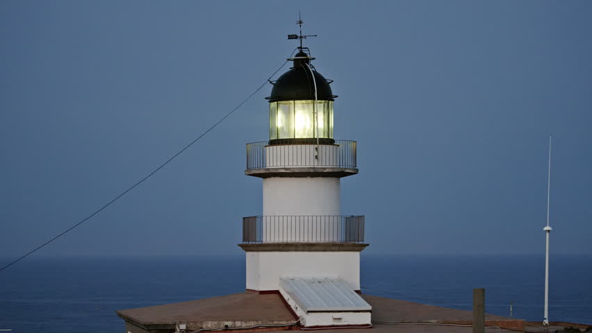 the light house in cap de creus in spain with light beam at night