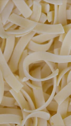 Closeup of raw fettuccine showcasing soft natural lighting and flour dust. Artisan kitchen scene highlighting unfished pasta with delicate textures and ambient warm tones