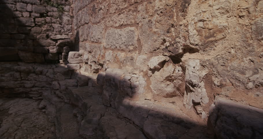 A stone wall with carved architectural details and a worn surface is shown in the old town.