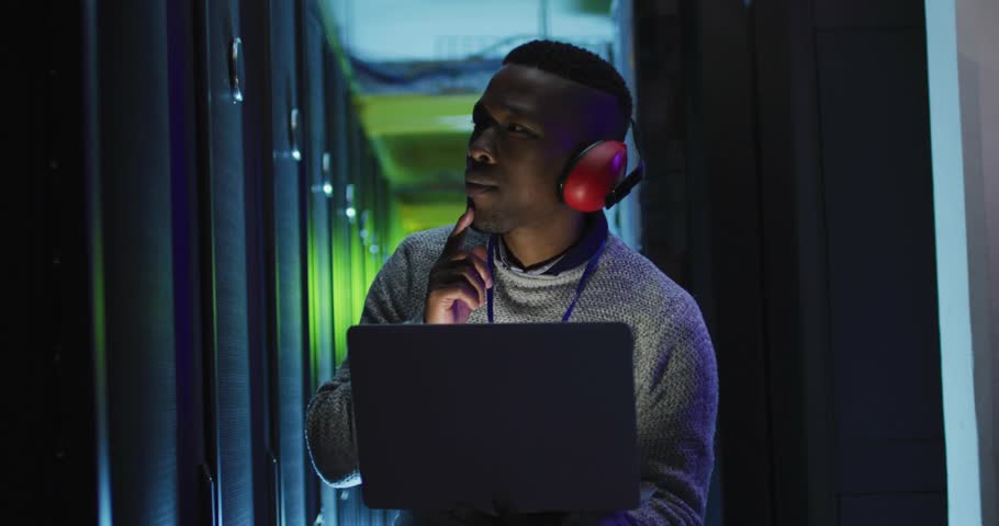 Male tech touching chin in data center, overlays appearing, pointing and managing social metrics. Server, rack, laptop, headphones, augmented, ui, hightech