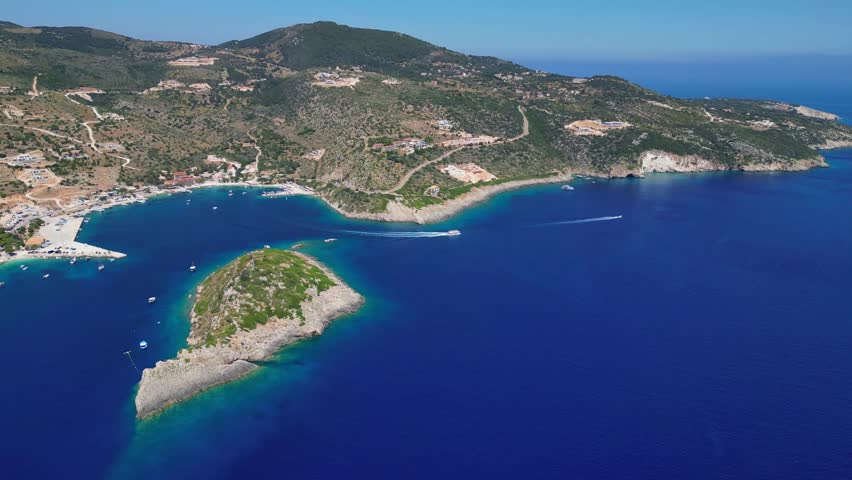 Scenic view of Agios Nikolaos port in Zakynthos with crystal blue water, sea caves, and a historic monastery rock. Beautiful Greek island landscape with tourist boats in the Ionian Sea.