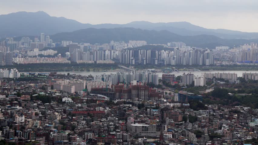 Seoul urban landscape featuring a dense residential area, Han River, and distant mountains