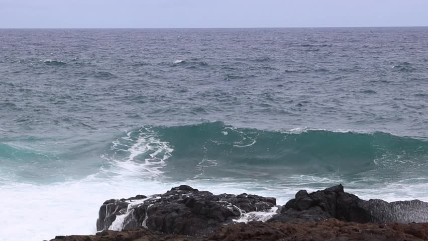A view of stormy waves in the Atlantic Ocean off a rocky coastline.