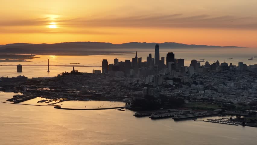 Golden sunset over San Francisco skyline with Bay Bridge and glowing bay waters. g.
