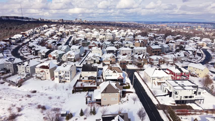 Cinematic aerial shot of snow-covered cottages and houses in the lakeside community of Fairmount, Halifax, Nova Scotia. Canada after winter snowstorm, serene suburban winter landscape 4K.
