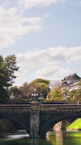 Scenic view of historic stone bridge and imperial palace castle structure over moat in Tokyo sunlight.