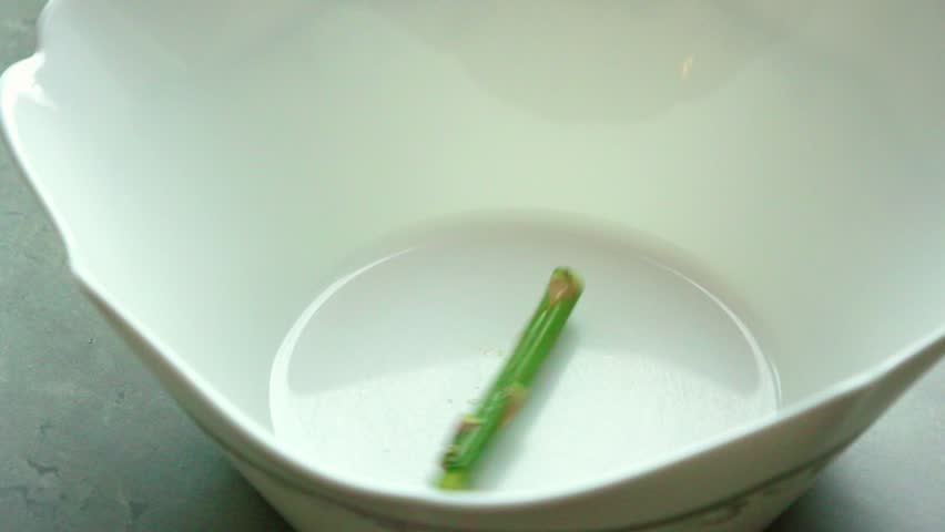 Close-up of seasoning a bunch of fresh asparagus in a bowl with oil, salt, and black pepper