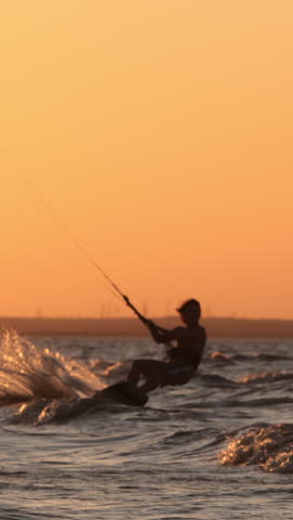 professional kitesurfer executing high jump trick sunset silhouette slow motion extreme water sports mastery