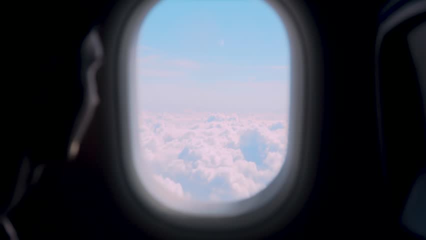 Airplane passenger looking through aircraft window over soft cloudscape during high altitude flight. Travel lifestyle aviation journey with serene sky horizon and sunlight atmosphere above clouds