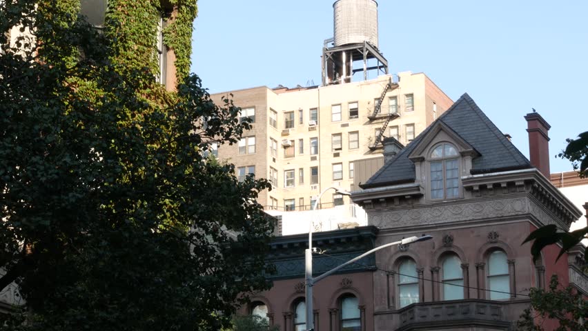 New York City urban building architecture, Manhattan rooftop, United States of America. Water tower on roof. Classic water tank. Ivy greenery on wall. Vine climber creeper plant on house, green leaves