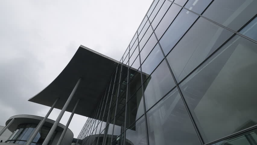 Upward perspective of the glass facade and concrete canopy roof of the Paul-Loebe-Haus parliament office building in the government quarter.