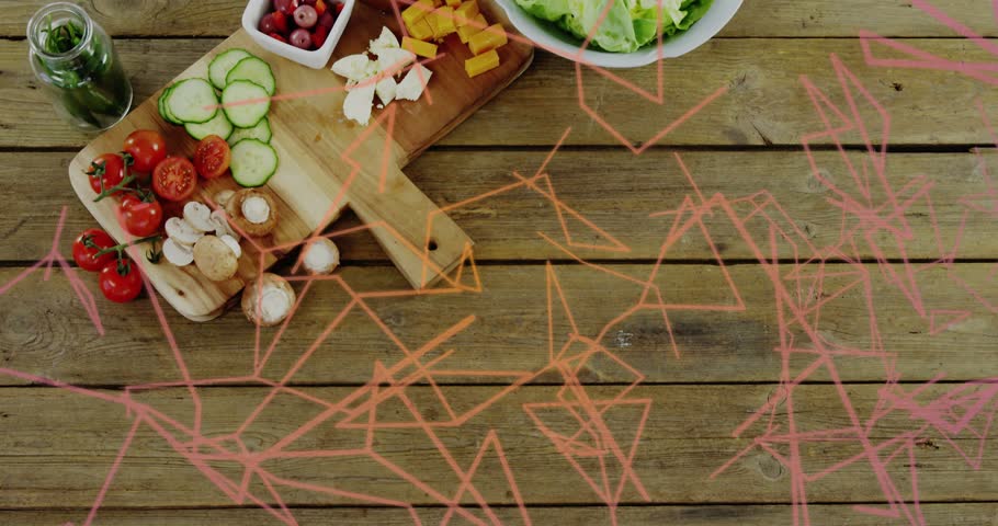 Displaying prepared salad ingredients on wooden cutting boards at kitchen table, with pink overlay. Cucumbers, tomatoes, lettuce, olives, cheese, herbs, overhead