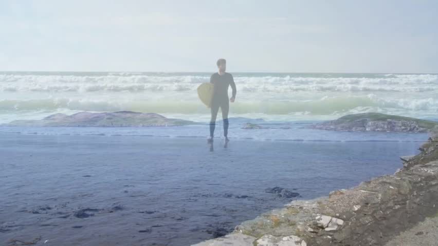 Surfer walking toward shore after exiting surf, holding yellow board, creating wet sand reflections. Beach, ocean, waves, wetsuit, solo, athlete, coastline