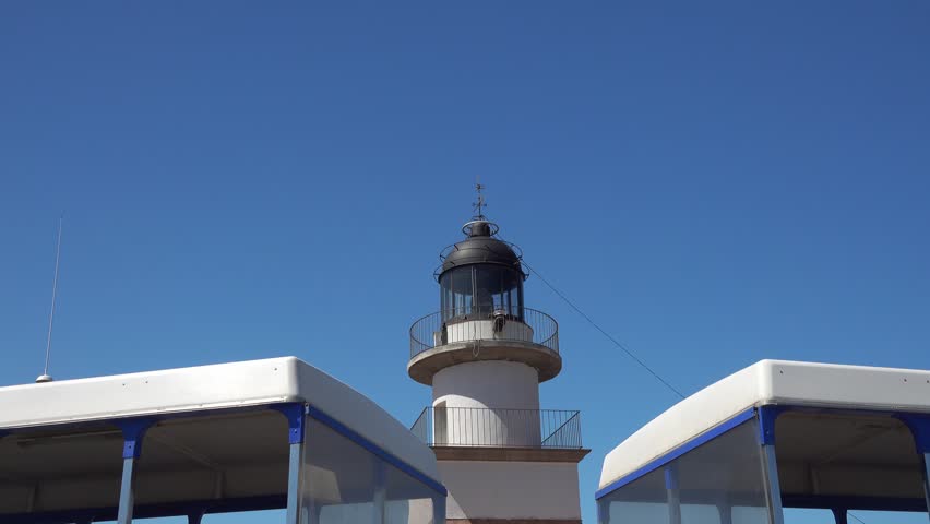 Lighthouse is surrounded by boats and blue sky. Cap de Creus, Spain