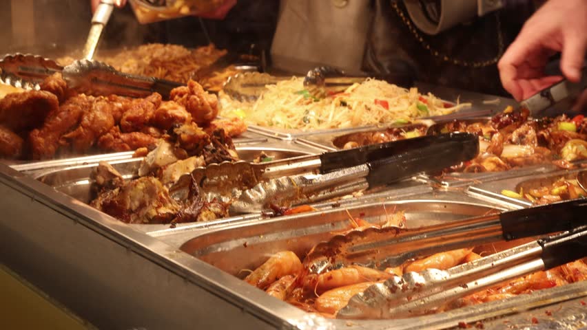 People putting food on plates in self service Chinese buffet restaurant
