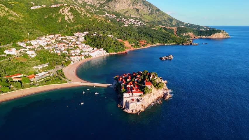 Aerial drone view of the beach and Sveti Stefan Island at sunset. Beautiful architecture and the blue Adriatic Sea. Sveti Stefan, Montenegro.	
