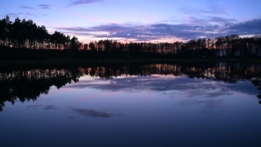 Forest pond at dusk, after sunset, sunset sky, calm water surface, forest in the distance, dark landscape