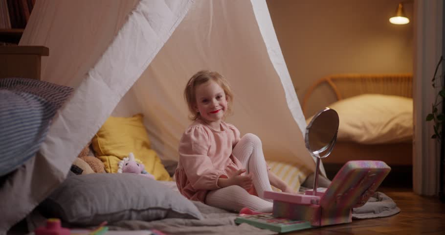 A joyful girl explores her colorful makeup kit inside a charming play fort filled with imagination and fun
