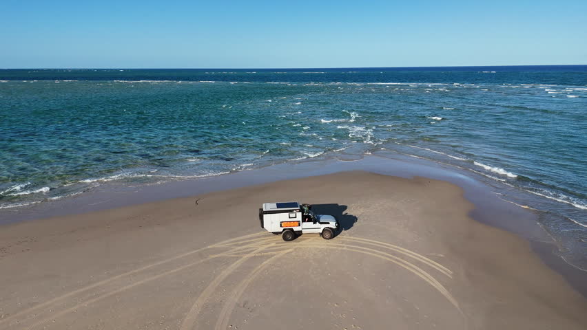 Aerial drone view of 4WD at Sandy Cape, northern tip of Fraser Island K gari, Queensland, Australia. White sand beach, turquoise water, iconic off-road travel destination.